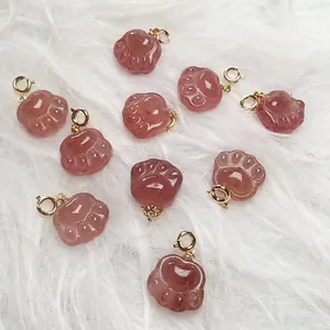 Detail of ten translucent pink crystal cat claw pendants on a soft white plush background