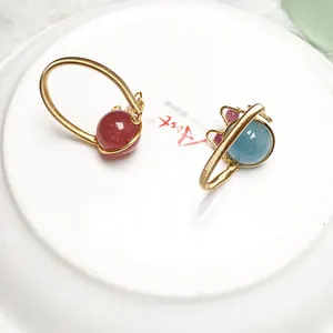 Makro-Detail handgefertigter 14K goldgefüllter Drahtringe mit Erdbeerquarz und Blausteinen