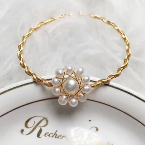 Detailed macro view of 14K gold wire handmade bracelet with freshwater pearl flower centerpiece
