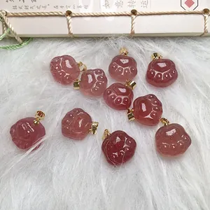 Close-up of strawberry quartz cat claw pendants with golden bails on white plush