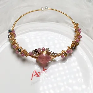 Close-up of handmade 14K gold wire wrapped bracelet with strawberry quartz and pearls