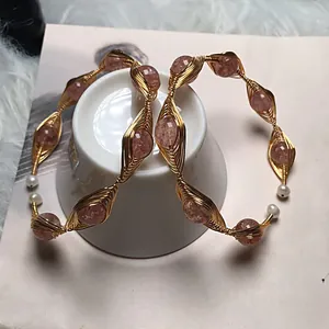 Detail of handmade gold wire-wrapped hoop earrings with pink strawberry quartz and pearls