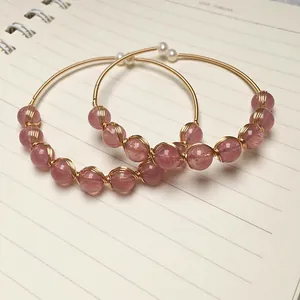 Close-up of strawberry crystal and pearl beads wrapped on 14K gold-filled wire bangle