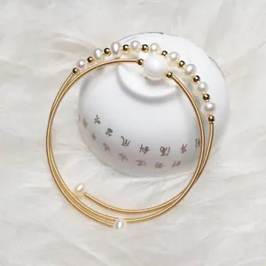 Detail of multilayer gold freshwater pearl wrap bracelet on traditional ceramic bowl