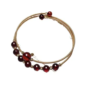 Multilayer 14K gold wire wrap bracelet with deep red amber beads on white background