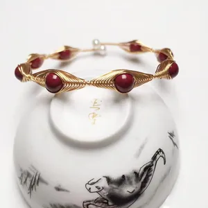 Detailed handcrafted gold wire-wrapped bracelet with red cinnabar beads and pearl accents