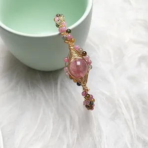 Detailed close-up of handmade strawberry quartz bracelet with 14K gold wire wrapping
