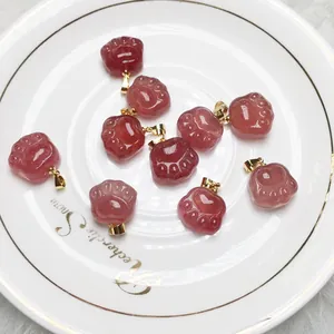 Pink strawberry crystal cat claw pendants with gold clasp on a decorative white dish