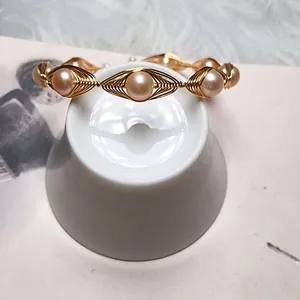 Detailed view of handmade gold wire-wrapped bracelet with round freshwater pearls