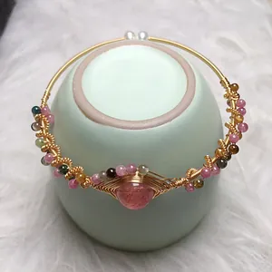 Handmade strawberry quartz and tourmaline 14K gold wire wrapped bangle on ceramic cup