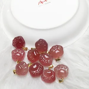 Set of 10 red strawberry quartz cat paw pendants with golden metal clips on fur background
