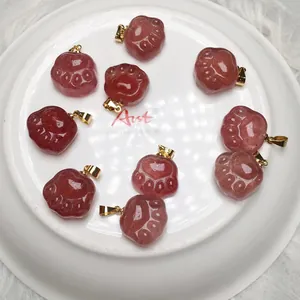 Red strawberry crystal cat paw pendants with gold hooks on white ceramic tray