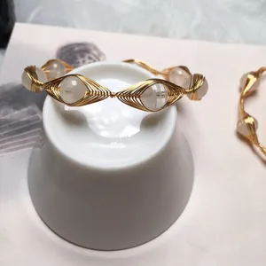 Macro detail of handmade gold wire-wrapped bracelet with translucent white crystal beads