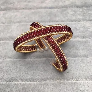 Detail of handmade gold wire wrap bracelet featuring red garnet beads and white pearls
