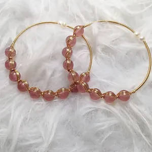 Close-up of handmade 14K gold wire strawberry quartz earrings with small white pearls