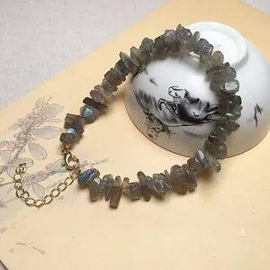 Verstelbare natuurlijke labradoriet armband met gouden karabijnsluiting op vintage papier