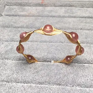 Brazalete de alambre dorado hecho a mano con cuentas de cuarzo fresa y una perla