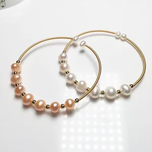 Detailed macro of 14K gold-filled wire bracelets featuring white and pink freshwater pearls