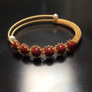 Elegant gold wire-wrapped open cuff bracelet with six red beads and two white pearls