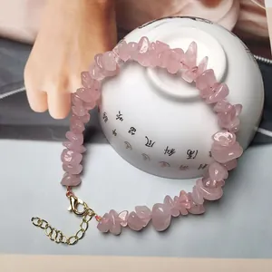 Handmade rose quartz crystal gravel bracelet with adjustable gold lobster clasp on porcelain