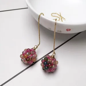 Detail view of colorful crystal ball earrings with gold chain in a minimalist setting