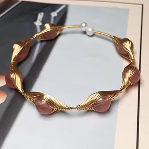 Detalle de gargantilla artesanal de cuarzo fresa envuelta en hilo de oro y perlas