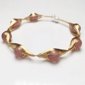 Detalle de pulsera de hilo dorado hecha a mano con cuarzo fresa y perlas blancas