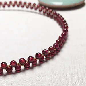 Macro detail of wine red garnet bead bracelet with 14K gold-filled wire weaving