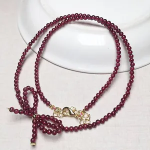 Detailed view of burgundy garnet beaded necklace with handmade bow and gold clasp