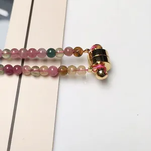 Makroaufnahme von bunten Turmalinperlen und goldenem Magnetverschluss am dreireihigen Armband