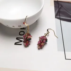 Close-up of handmade tourmaline grape earrings with colorful beads on a gold hook