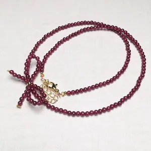 Elegant garnet beaded necklace featuring golden bow accent and adjustable clasp closure