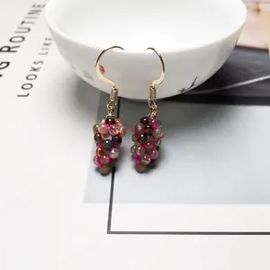 Detailed shot of multi-color crystal bead cluster earrings hanging on a white ceramic bowl