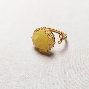 Macro van 14K goudgewikkelde barnsteen roos ring met handgemaakte draadweefsel details