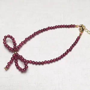 Elegant deep red garnet beaded necklace with gold bow charm and adjustable lobster clasp