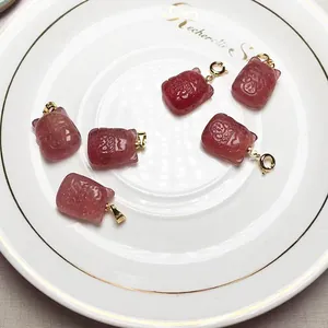 Pendentifs de chat porte-bonheur en cristal fraise avec détails dorés sur assiette blanche