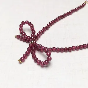 Close-up of deep red garnet beaded necklace with a vintage gold bow design