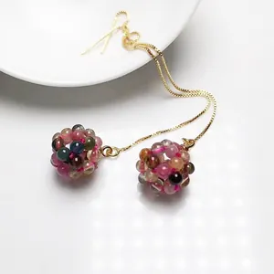 Detail of colorful tourmaline crystal bead ball pendant on long gold chain earrings
