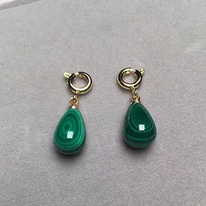 Dettaglio di orecchini di malachite a goccia con cerchi d'oro su velluto grigio