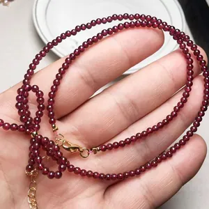 Macro detail of garnet beaded necklace featuring gold-tone lobster clasp and extension chain