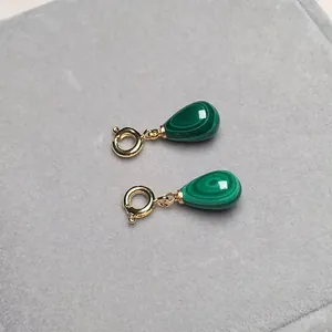 Macro di ciondoli a goccia in malachite con chiusure a molla dorate su velluto grigio