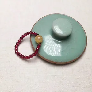 Anello elastico in granato con perla di quarzo rutilato e accenti dorati su porcellana