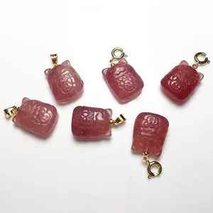 Détails macro des pendentifs en quartz fraise avec motifs de chat et fermoirs dorés