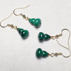 Detailed view of malachite gourd drop earrings with polished gold metal hooks