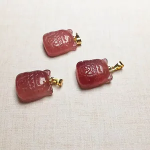 Détail macro de trois pendentifs sacs porte-bonheur en quartz fraise et fermoirs dorés