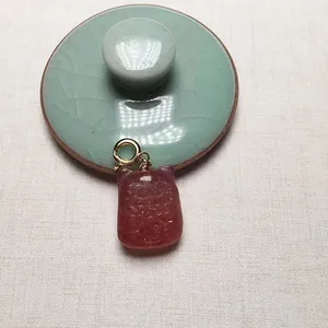 Détail macro du pendentif en quartz fraise avec motif sculpté sur couvercle en céladon