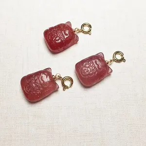 Trois pendentifs en cristal fraise rouge avec fermoirs mousquetons dorés sur lin