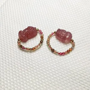 Detail of beaded rings with strawberry quartz pixiu charms and multi-color gemstones