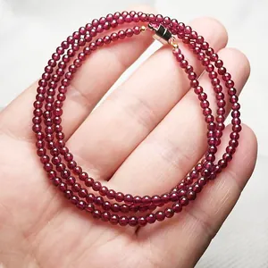 Three-layer dark wine red garnet bead bracelet with metallic clasp on light textured background