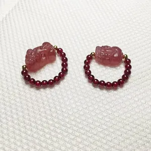 Detailed macro view of strawberry quartz PiXiu charm and garnet beaded ring for women
